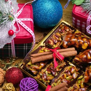 Oriental sweets with nuts and cinnamon sticks surrounded by Christmas gifts and festive decorations